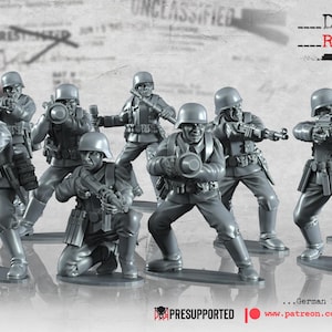 May include: A set of 9 grey plastic miniature figures of German Luftwaffe soldiers, holding various weapons, with the text "...German Luftwaffe Field Division" and "www.patreon.com/madox_historicalminis" below.