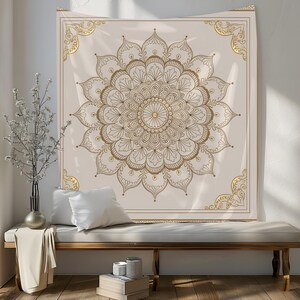 May include: A white tapestry with a gold mandala design. The mandala is intricate and detailed, with a circular pattern of flowers and leaves. The tapestry is hanging on a wall, and there is a white couch in the foreground.