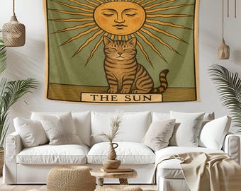 以下が含まれることがあります： 人間の顔をした太陽の下に座っている猫が描かれたタペストリー。タペストリーは緑色の背景で、下部に「THE SUN」という文字が書かれています。