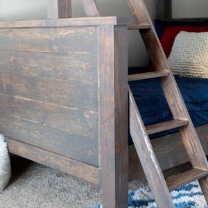 May include: A wooden bunk bed frame with a ladder. The frame is stained a dark brown color and has a rustic look. The ladder is made of the same wood and has four steps.