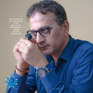 May include: A man wearing glasses and a blue shirt examines a piece of jewelry with a magnifying glass. The text "WE MAKING EXCELLENT AND MICROW FINISHING WITH LOVE FOREVER" is visible in the image.