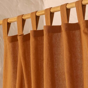 May include: A set of brown linen curtains with a simple design and a wooden rod. The curtains have a relaxed, casual look and would be a great addition to any home.