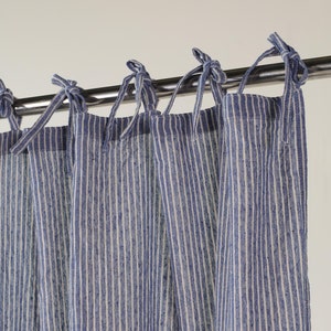 May include: Blue and white striped curtains with a simple tie-top design. The curtains are hung on a silver curtain rod.