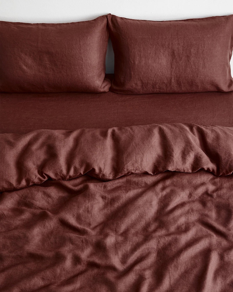 May include: A deep red linen duvet cover and two matching pillowcases. The duvet cover is crumpled and has a soft, textured look.