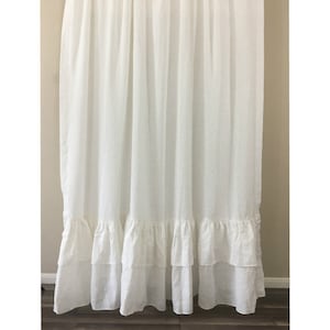 May include: White linen shower curtain with a double row of ruffles at the bottom.
