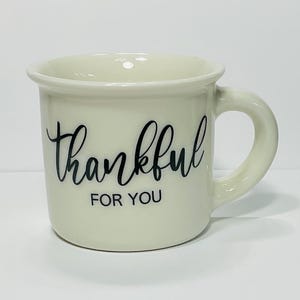 Puede incluir: Taza de cer&aacute;mica color crema con asa curva. La taza presenta las palabras "thankful FOR YOU" en escritura negra. La taza est&aacute; dise&ntilde;ada para bebidas y tiene un borde redondeado.