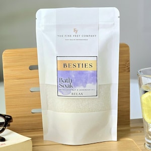 Peut inclure: Pochette blanche avec une étiquette qui indique "The Fine Feet Company" et "Besties Bath Soak with Coconut & Lavender Oil Relax".