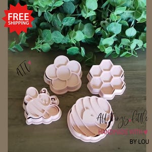 May include: Four pink plastic cookie cutters in the shapes of a flower, a honeycomb, a bee, and a swirl. The phrase "All Things Little Handmade with Love by Lou" is printed on the bottom right of the image.