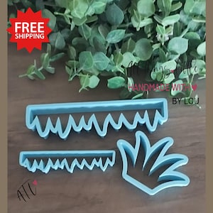 May include: Three light blue plastic cookie cutters in the shape of a saw, a smaller saw, and a plant. The text "All Things Little Handmade With By Lou" is visible. The image also includes the text "FREE SHIPPING".