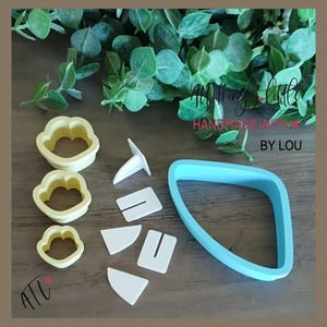 May include: A set of three yellow cloud-shaped cookie cutters, a large light blue triangular cutter, and four white plastic assembly pieces. The text "All Things Little HANDMADE WITH LOVE BY LOU" is visible in the upper right corner of the image.
