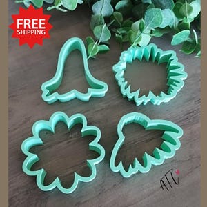 May include: Four light green cookie cutters in various floral shapes. The cutters include a bell shape, a spiky circle, a scalloped circle, and a petal shape. The image includes a red starburst with the words "FREE SHIPPING".