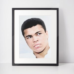 Könnte beinhalten: Ein schwarzweißes gerahmtes Foto eines jungen Mannes mit kurzen schwarzen Haaren. Er schaut nach oben und nach rechts, mit einem ernsten Gesichtsausdruck.