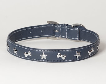 May include: A navy blue dog collar with silver star and bone-shaped studs. The collar is made of leather and features white stitching along the edges. It has a silver-colored metal buckle and a D-ring for leash attachment.