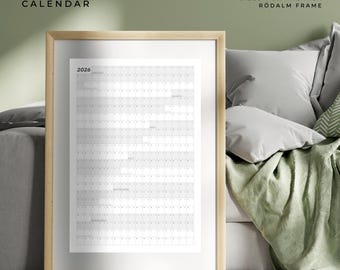 May include: A framed 2026 year-at-a-glance calendar. The calendar is white with a grid layout and is sized at 24" x 36". The frame is light wood-toned. The text "2026 YEAR AT A GLANCE CALENDAR" is at the top.