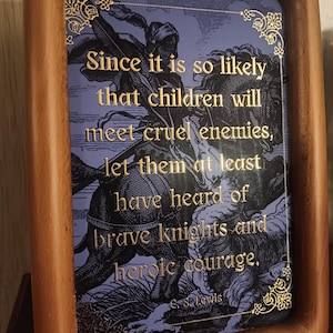 May include: A rectangular wooden frame containing a print with a blue background featuring a knight on horseback. The text in gold lettering reads: Since it is so likely that children will meet cruel enemies, let them at least have heard of brave knights and heroic courage. C. S. Lewis.