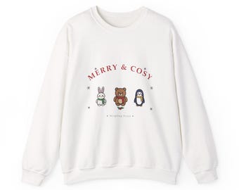 May include: A white long-sleeve sweatshirt featuring the red text MERRY & COSY. Below the text are three small cartoon animals: a white rabbit with a green scarf, a brown bear with a red scarf, and a penguin with a yellow scarf. Wispling Press is printed below.