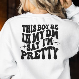 May include: White sweatshirt with black text that reads "This boy be in my DM say I'm pretty" in a retro font.