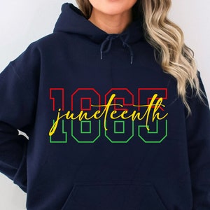 Peut inclure: Un sweat-shirt bleu marine avec un motif rouge, vert et jaune qui dit "Juneteenth 1865".