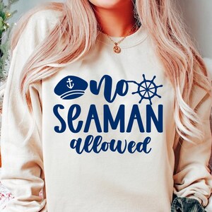 Puede incluir: Una sudadera de color crema con un gráfico azul que dice "no seaman allowed". El gráfico incluye un gorro de marinero con un ancla y un timón.