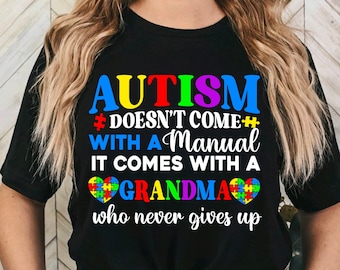 May include: Black t-shirt with the text "AUTISM DOESN'T COME WITH A MANUAL IT COMES WITH A GRANDMA who never gives up". The text is in white and the word "AUTISM" is in rainbow colors. A heart with a puzzle piece design is next to the word "GRANDMA".