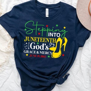 May include: Navy blue t-shirt with the text "Stepping into Juneteenth with God's Grace & Mercy June 19, 1865" and a yellow high heel shoe graphic.