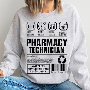 Puede incluir: Sudadera gris con un diseño gráfico negro que dice "Técnico de farmacia". El gráfico incluye iconos para el trabajo duro, la multitarea, la alta cualificación y la necesidad de cafeína. También se incluye el texto "Advertencia: Puede contener trazas de sarcasmo".