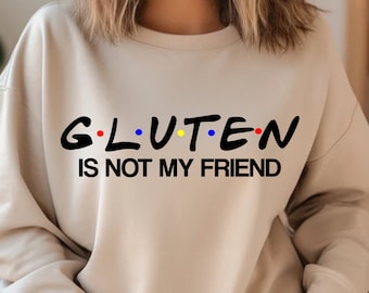 May include: A beige sweatshirt with the text "G.L.U.T.E.N. IS NOT MY FRIEND" in black. The letters are outlined in red, blue, and yellow dots.