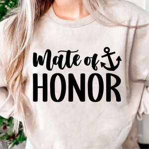 May include: A beige sweatshirt with the text "mate of honor" and an anchor symbol in black.
