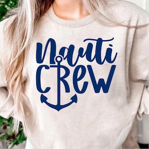 May include: A beige sweatshirt with a blue anchor and the text "Nauti Crew" in a navy blue script font.