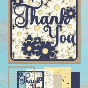 May include: A digital cut file design featuring the words "Thank You" in a decorative script font. The design is surrounded by a pattern of white flowers with yellow centers on a dark blue background. The design is intended for use with a cutting machine to create a card or other craft project.
