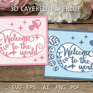 May include: Two 3D layered papercut cards with a baby footprint design. The card on the left is pink and the card on the right is blue. Both cards feature the text "Welcome to the world" and a pacifier.