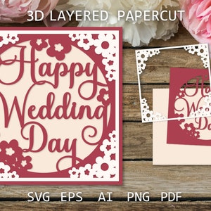 以下が含まれることがあります： 白い花の縁取りと中央に「Happy Wedding Day」と書かれた円形がある赤い紙切りカードです。