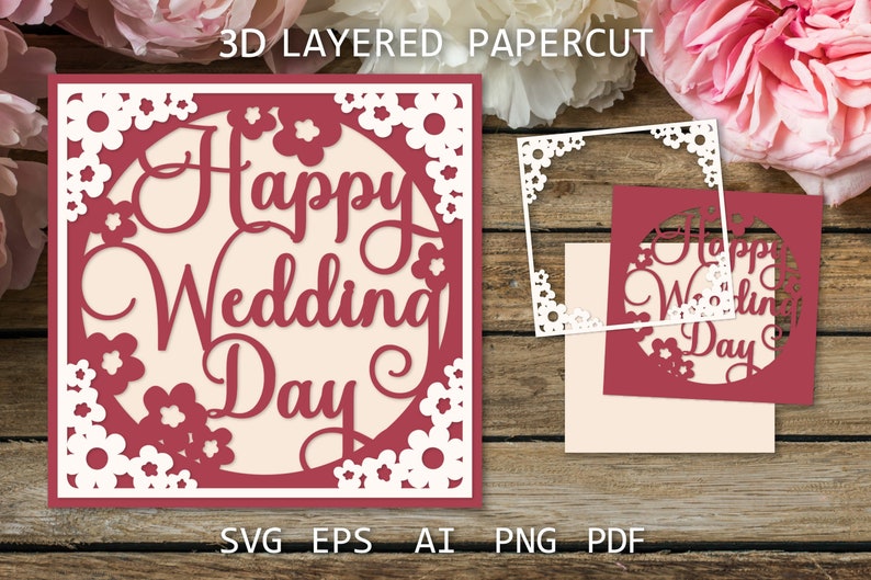 以下が含まれることがあります： 白い花の縁取りと中央に「Happy Wedding Day」と書かれた円形がある赤い紙切りカードです。