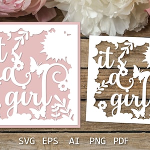 May include: A white paper cut-out design with the text "it's a girl" surrounded by flowers and butterflies. The design is on a pink background.