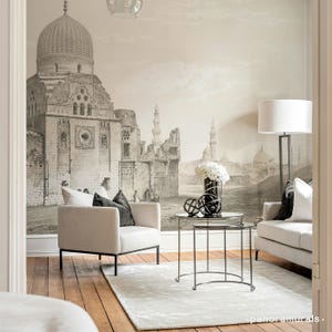 Puede incluir: Un salón con un gran mural en tonos sepia que representa una escena de una ciudad antigua. La habitación cuenta con un sofá y un sillón de color claro, una alfombra y dos mesas auxiliares redondas. Una lámpara de pie y objetos decorativos completan el espacio.