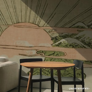 May include: A round wooden table with a light brown finish and black chairs. The background features a mural with a landscape design in shades of pink, green, and beige. The mural has a Japanese-inspired aesthetic.