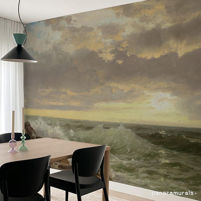 K&ouml;nnte beinhalten: Ein Esszimmer mit einem Wandbild, das eine dramatische Meereslandschaft mit tosenden Wellen unter einem bew&ouml;lkten Himmel zeigt. Der Raum umfasst einen Holztisch, schwarze St&uuml;hle und dekorative Kerzen.