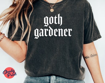 Könnte beinhalten: Ein dunkelgraues T-Shirt mit dem Text "goth gardener" in weißer gotischer Schrift.