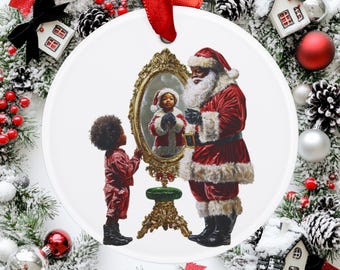 May include: A white Christmas ornament featuring a depiction of Santa Claus and a child looking in a mirror. The mirror reflects the child dressed as Santa. The ornament has a red ribbon for hanging and is surrounded by festive decorations.