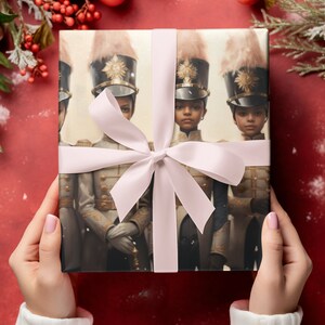 May include: Gift-wrapped present featuring a detailed illustration of soldiers in ornate uniforms and tall hats. The gift is tied with a light pink ribbon and bow. The background is a festive red with holiday decorations.