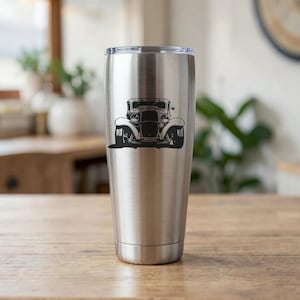 May include: A stainless steel tumbler with a black vintage car graphic. The car is a classic model with large headlights and a detailed front end. The tumbler is cylindrical and has a silver lid.
