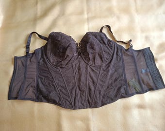 May include: A black corset with adjustable straps and a hook-and-eye closure. The bodice features intricate floral embroidery and sheer mesh panels on the sides. The underbust garment is designed for support and shaping.