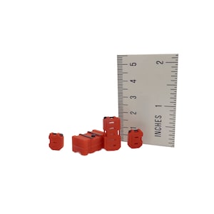 May include: Four red plastic fuel containers of different sizes, with a ruler measuring up to 12.7 cm for scale.