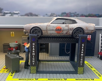May include: A miniature garage scene featuring a weathered, rusty car on a lift. The car has the "GULF" logo on the side. A small figure of a mechanic is working on the car. The lift has the word "GEARMIGHT" on the side.