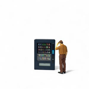 Puede incluir: Una persona en miniatura se encuentra frente a una máquina expendedora. La máquina expendedora es negra y tiene un frente de vidrio con filas de bocadillos y bebidas coloridos. La persona lleva una camisa marrón y pantalones azules.