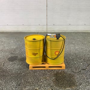 May include: Two yellow metal barrels with a black hose and nozzle on a wooden pallet. The barrels have a black and red logo on them.