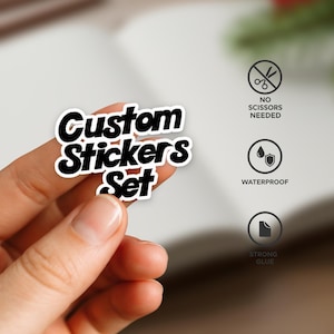 May include: A white sticker with black text that reads "Custom Stickers Set." The sticker is held by a hand. Icons indicate the stickers are waterproof, have strong glue, and require no scissors.