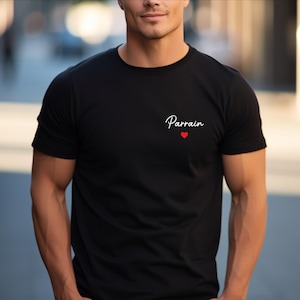 Puede incluir: Camiseta negra con la palabra "Parrain" en escritura cursiva y un peque&ntilde;o coraz&oacute;n rojo. La camiseta es de cuello redondo y parece estar hecha de un material suave.