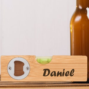 Könnte beinhalten: Ein Holz-Wasserwaage mit einem Flaschenöffner und einer Libelle. Die Wasserwaage ist mit dem Namen "Daniel" graviert.