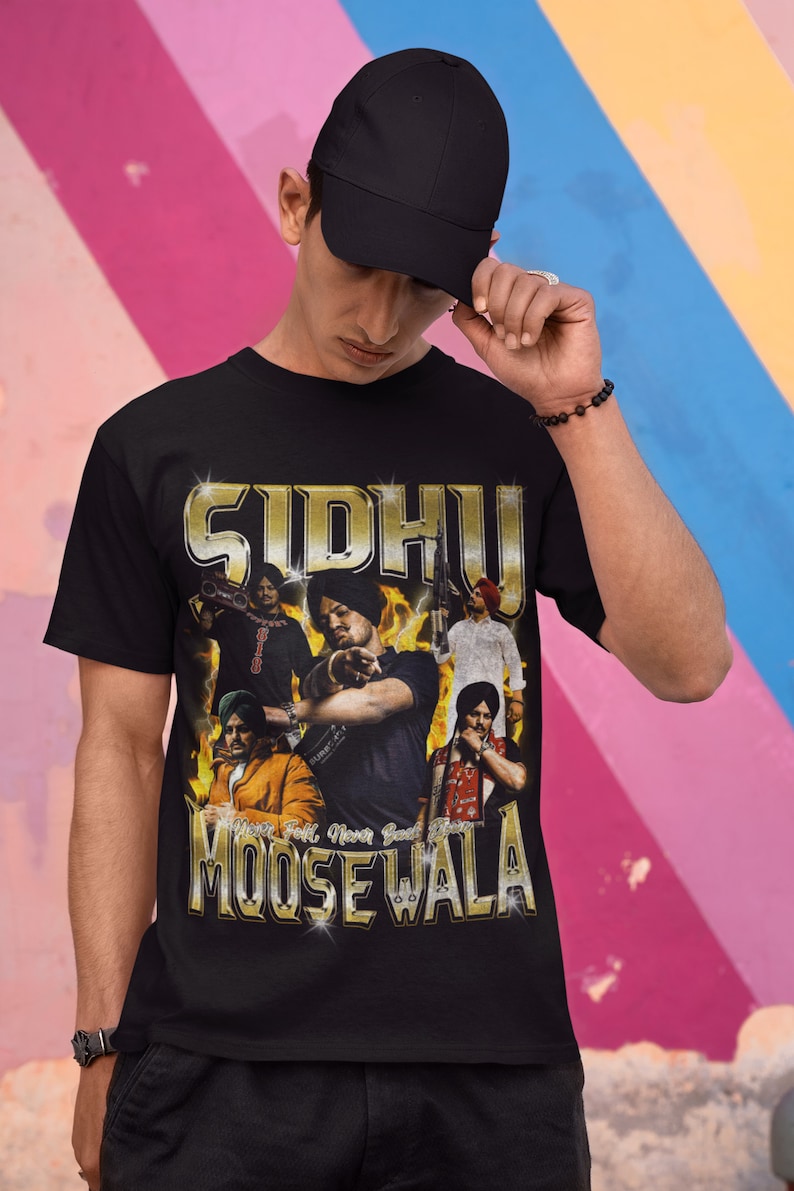 May include: Black t-shirt with a gold graphic print of a group of men wearing turbans. The graphic includes the text "Sidhu Moose Wala" and "Never Fall, Never Back Down".